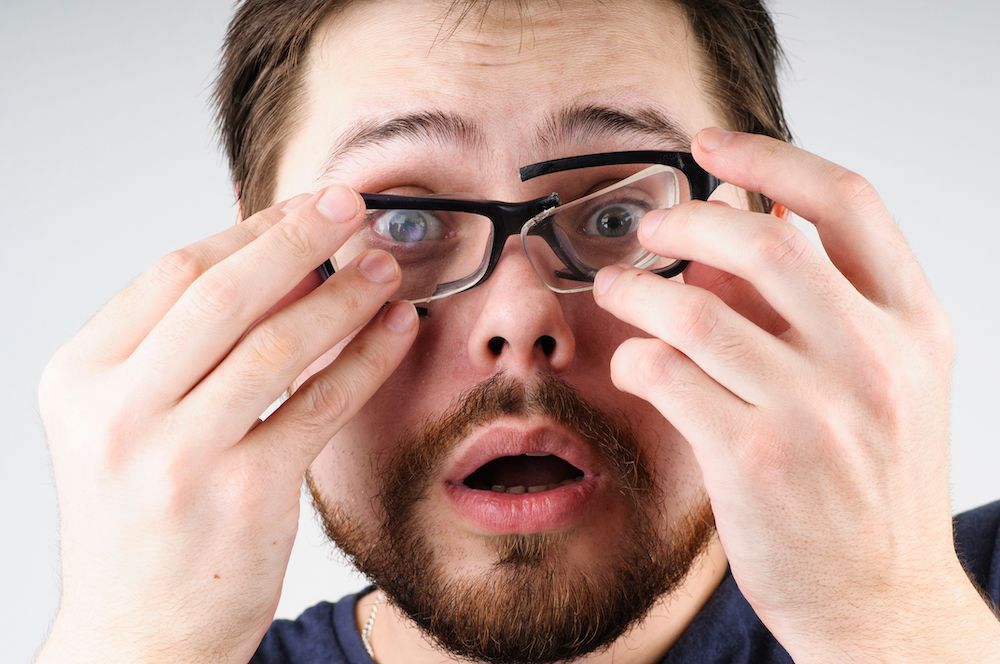 man fumbling with broken glasses