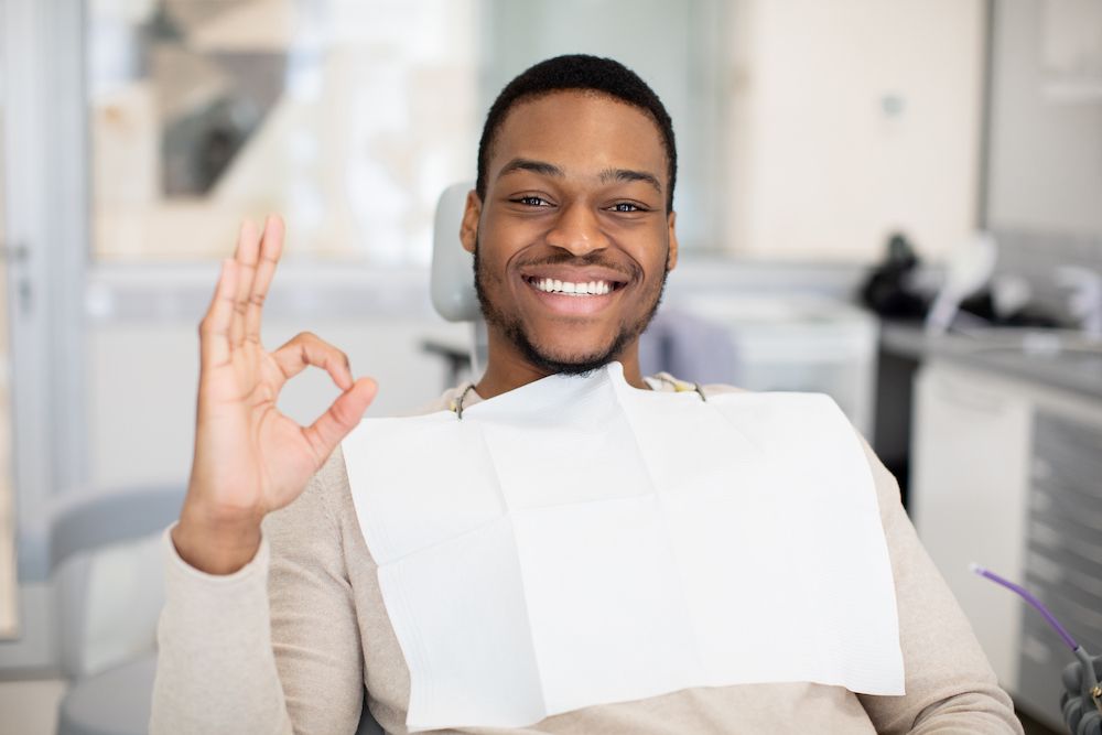 smiling young adult man giving an a-ok hand sign