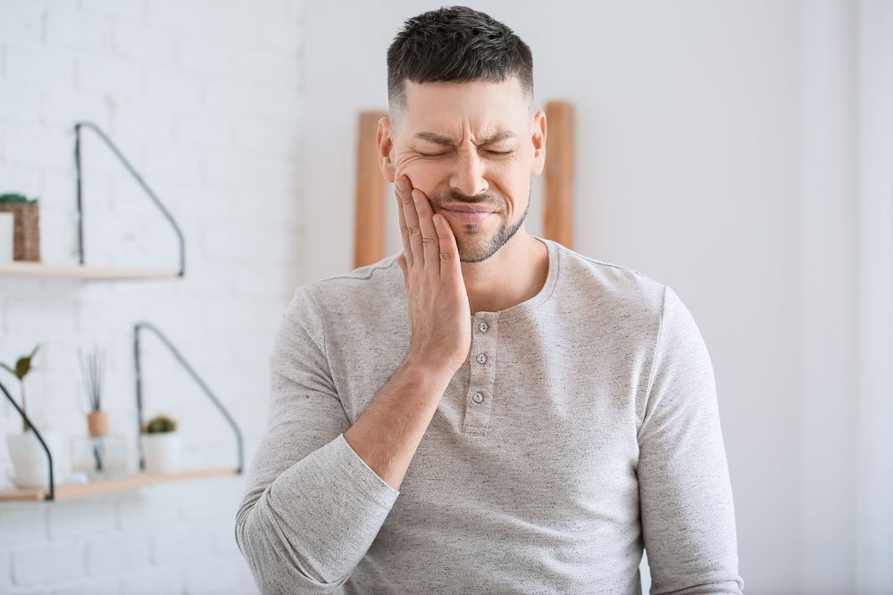 man holding his jaw in pain