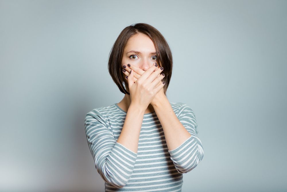 woman with bad breath holding her mouth
