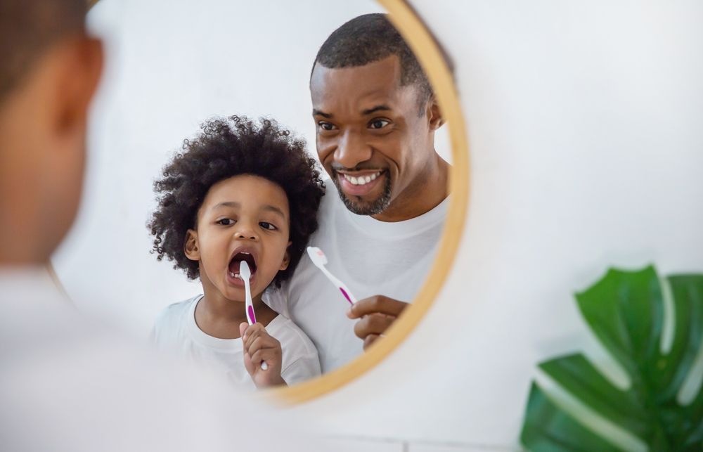 Father and child looking in the mirror brushing teeth