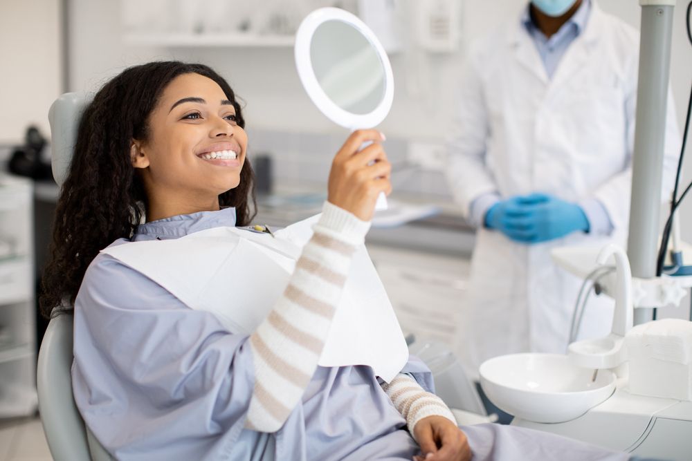 woman at the dentist looking at her teeth in a mirror