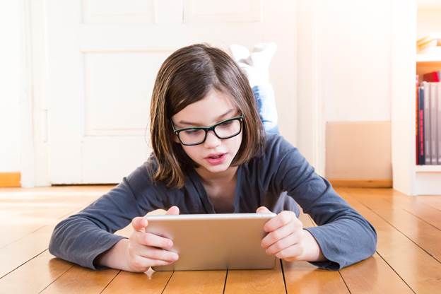 Young girl wearing glasses and looking at a notebook on the floor