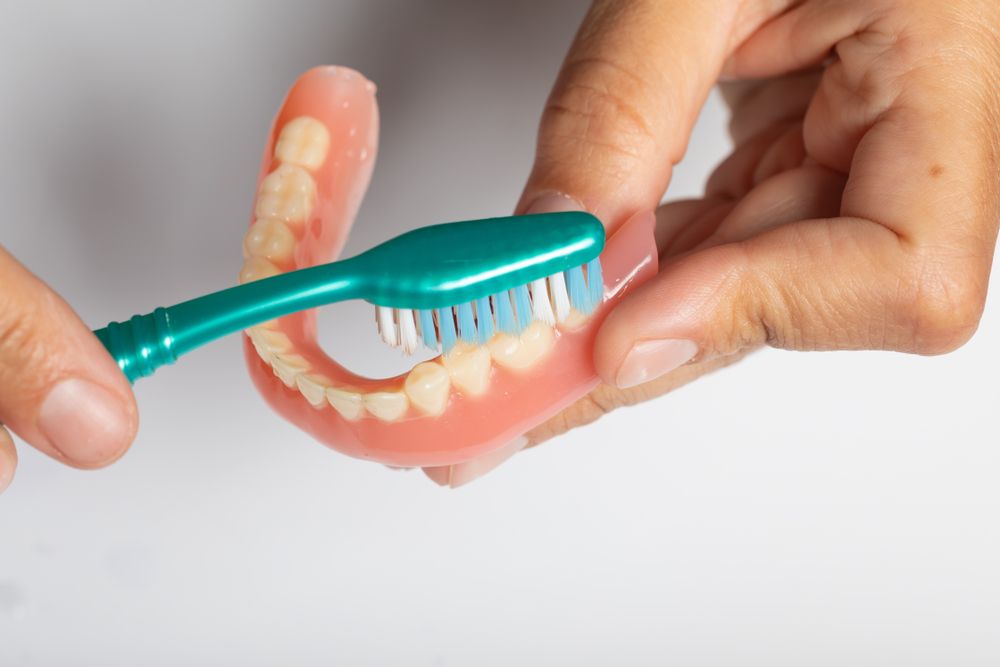 cleaning denture with toothbrush