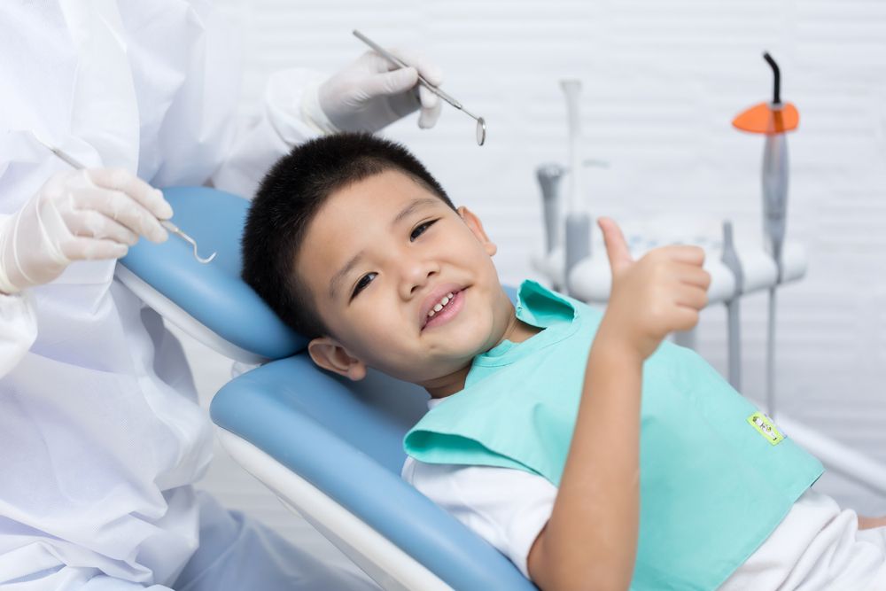Dentist examining Asian little boy teeth in clinic.​​​​​​​
