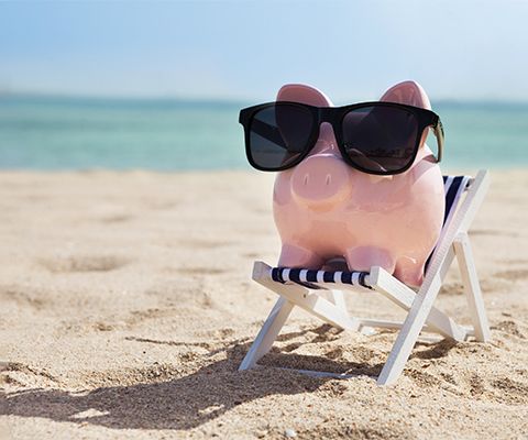 Piggy bank with sunglasses from eye doctor sitting on a chair at the beach in Tequesta, FL