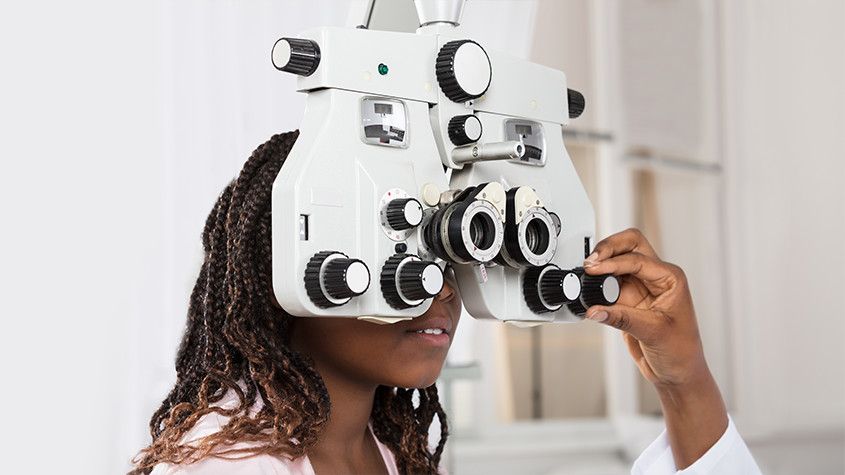girl looking into eye exam phoropter for eye health