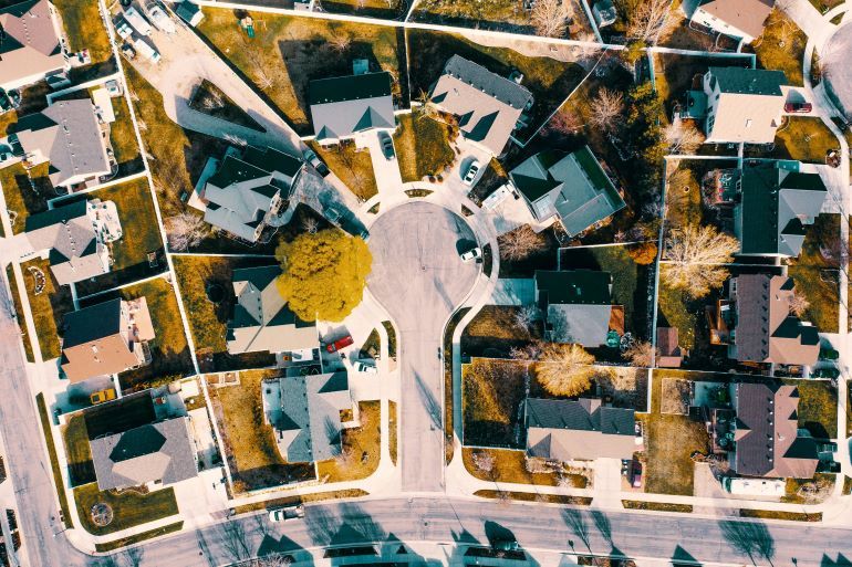 Aerial view of a suburban HOA neighborhood with organized homes, streets, and shared green spaces.