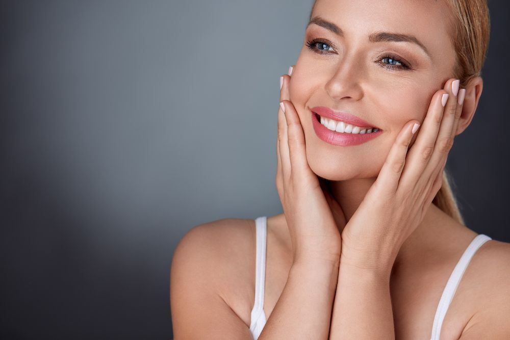 woman with her hands on her face smiling