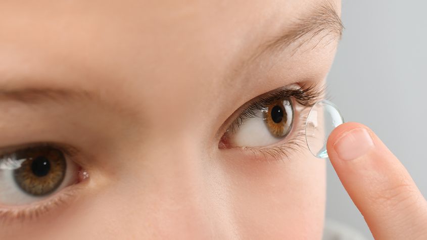 child placing a contact lens in their eye
