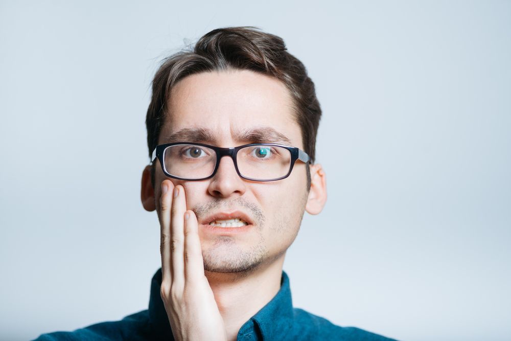 man holding his jaw in pain