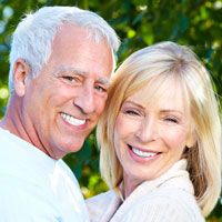 Middle-aged couple standing outdoors and hugging while smiling