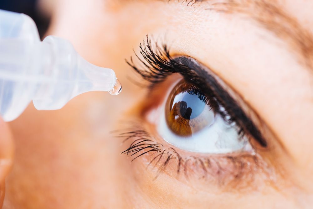 Macro pose of woman dripping eye with eyes drops