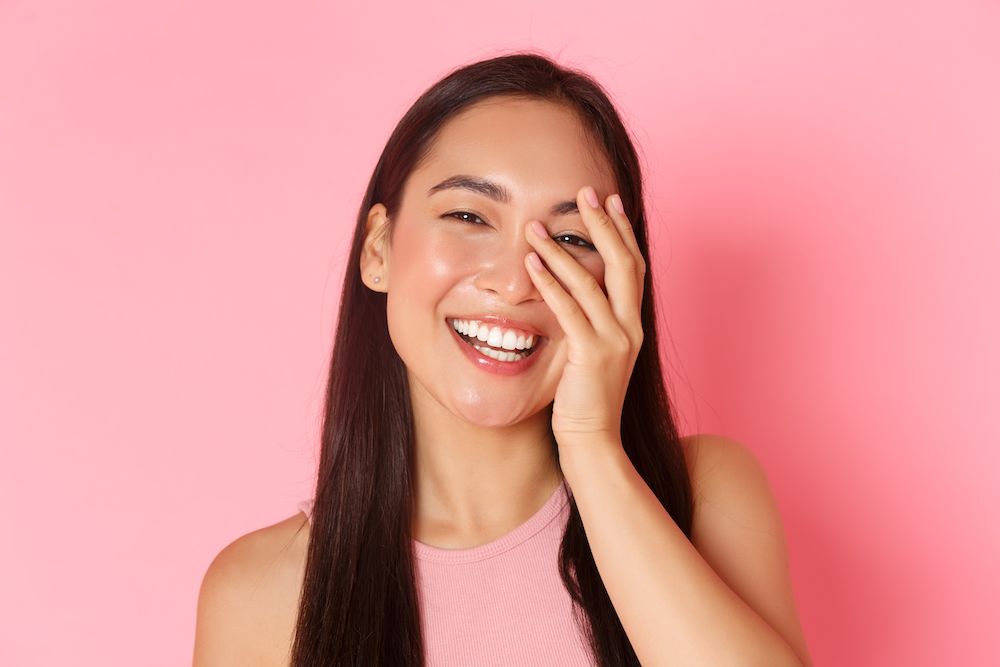 woman smiling in front of a pink background