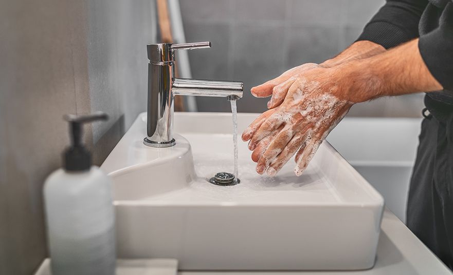 Washing hands with soap and hot water at home bathroom sink