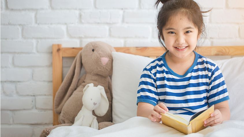 child reading book in bed