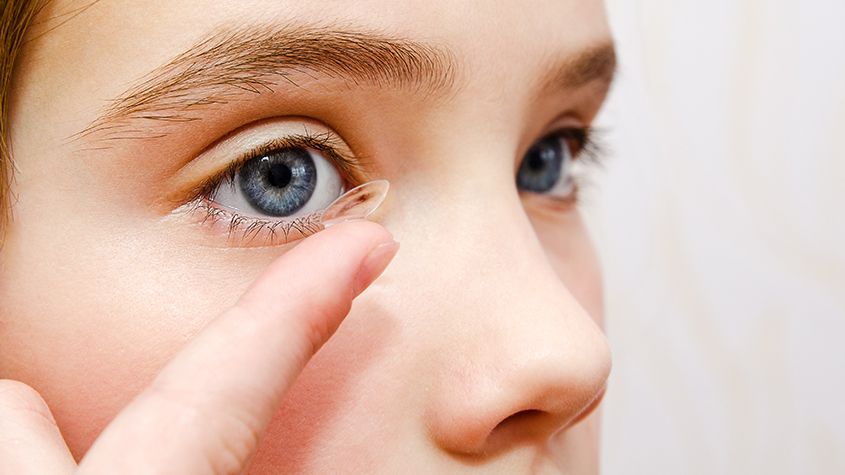 child placing a contact lens in their eye