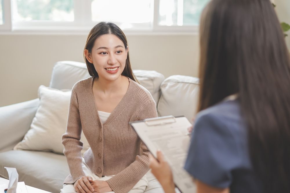 Psychology, depression. smile asian young woman patient mental explained symptom with psychologist, psychiatrist while doctor woman taking notes at clinic. Encouraging, therapy.