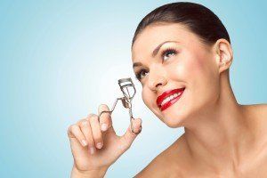 Beautiful woman with eyelash curler