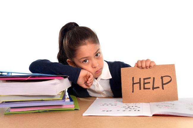 Girl with stack of books, upset. She is leaning on books to right hand side, and holding a sign that say 