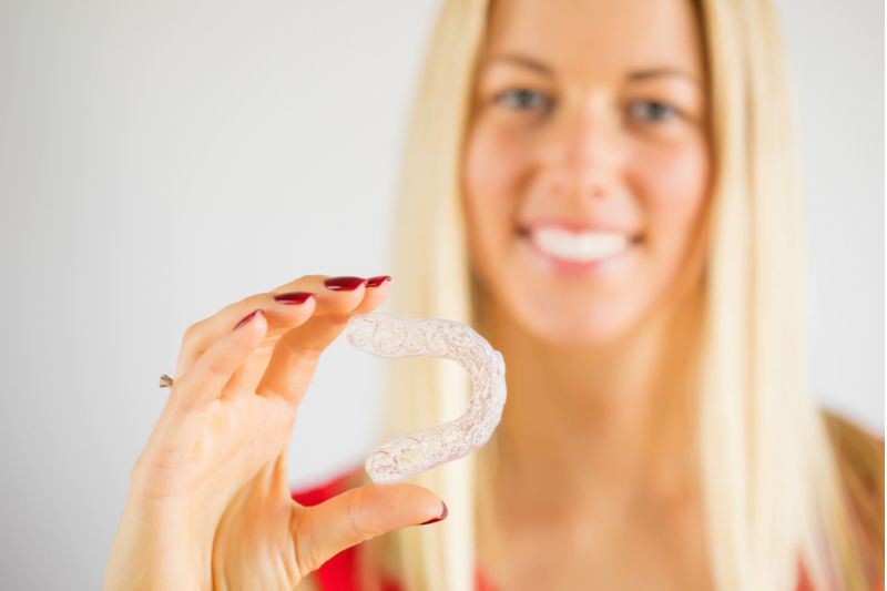 Blonde Lady Holding Invisalign​​​​​​​