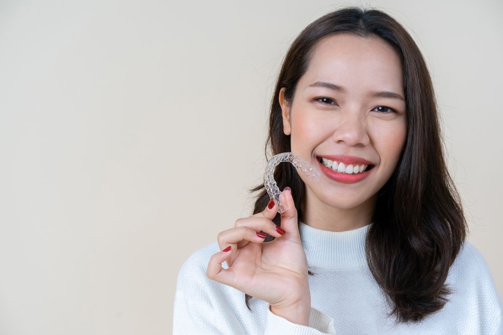 woman holding a mouthguard and smiling​​​​​​​