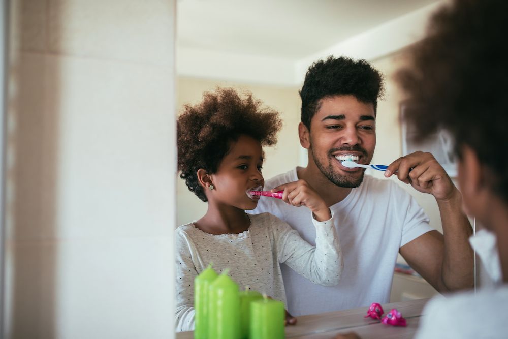 dad and daughter brushing their teeth together​​​​​​​