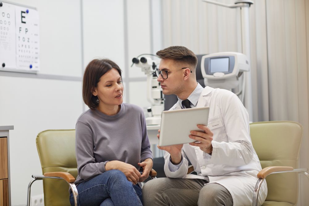 ophthalmologist using digital tablet while consulting patient