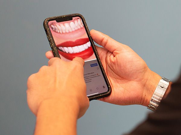 A person holding a cell phone with a tooth on it.