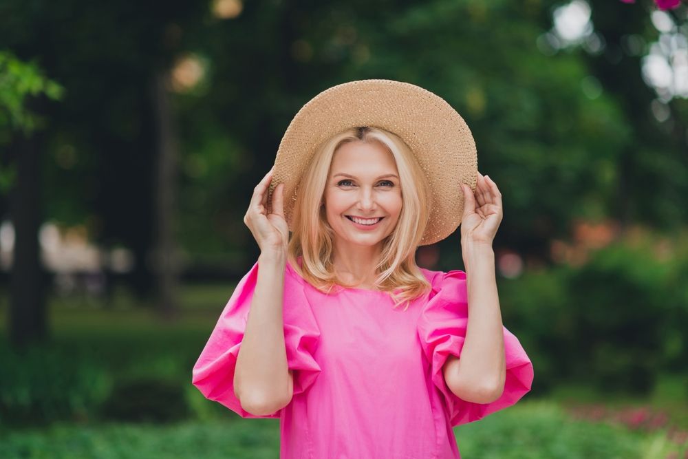 Woman in a garden with a large hat, just injected dermal fillers