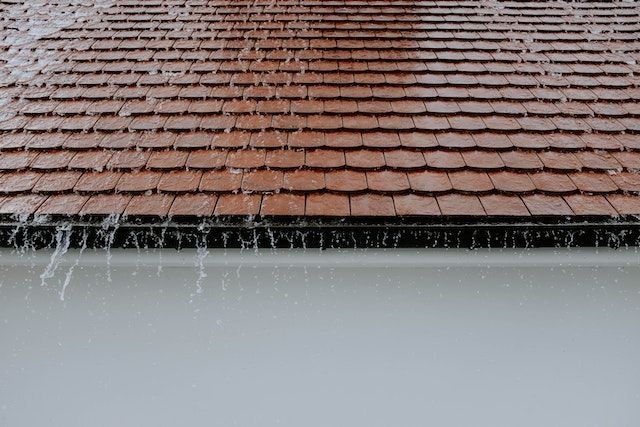 A roof with rain falling down. When beginning to prepare your rental property for fall it is recommended to start from the outside