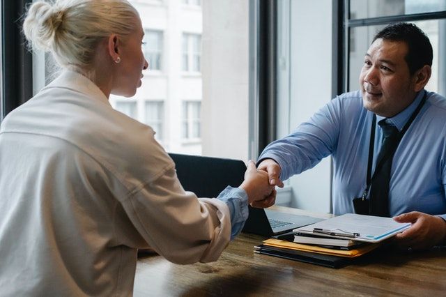 A man and a woman shaking hands in an office.